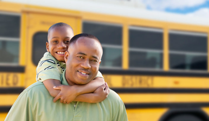 Father and son in front of a school bus