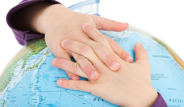 Child's hands hugging a globe