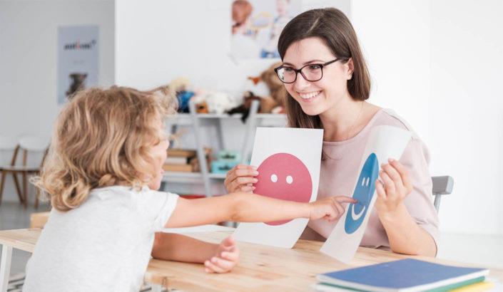 Teacher showing a student images of faces as part of special needs learning