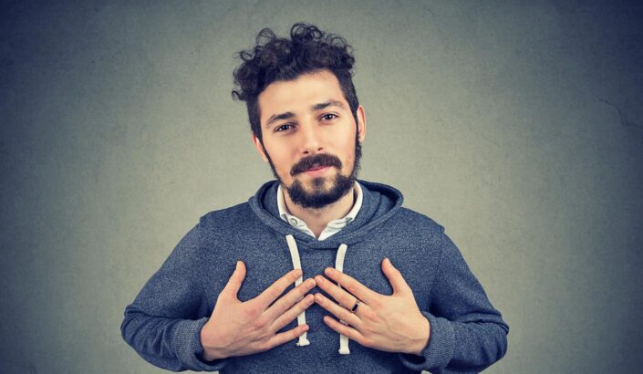 Man gestures towards his chest to express earnestness and humility