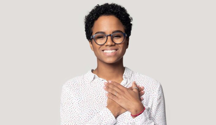 A Black woman standing with her hands on her chest to represent forgiveness