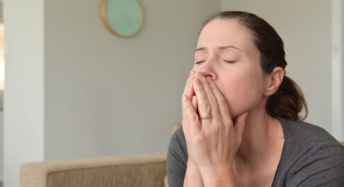 a white woman holds her hands in front of her mouth with her eyes closed, as if contemplating
