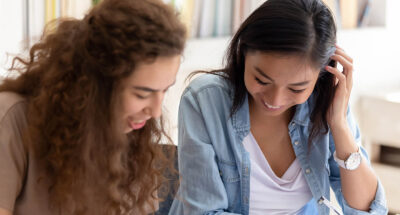 Two happy diverse girls college friends studying together in campus