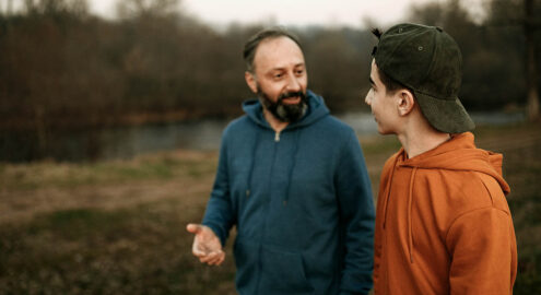 Father and son having a discussion while on a walk in the woods.