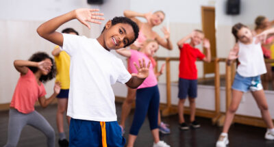 A smiling black boy showing dancing with classmates