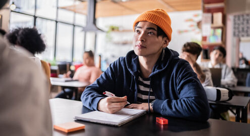 Non-binary student writing poetry in class