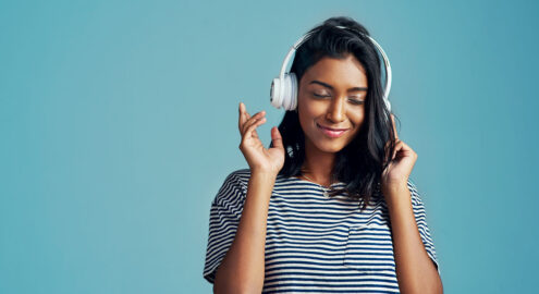 Cropped shot of a young woman wearing headphones against a blue background