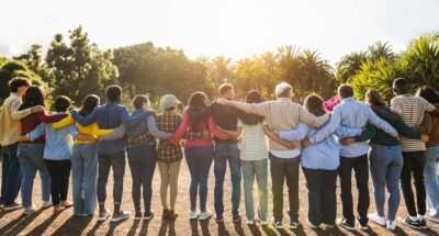 Group of multigenerational educators standing together with arms around each other, indicating a sense of belonging and community