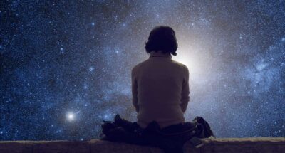 Young woman sitting on the ground and watching the stars. Stars are digital illustration.