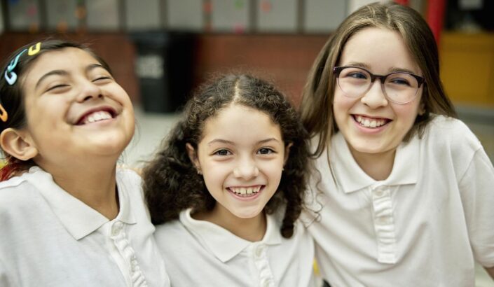 Three diverse students in school uniforms look happy and content at school