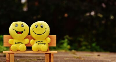 Two small minifigures smiling and sitting on a bench