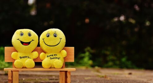 Two small minifigures smiling and sitting on a bench