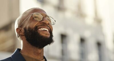 Black man with beard and glasses stands up looking at something awe-inspiring