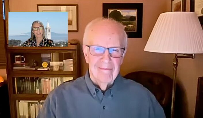 Smiling man looking at camera on zoom call with smaller screen featuring woman smiling