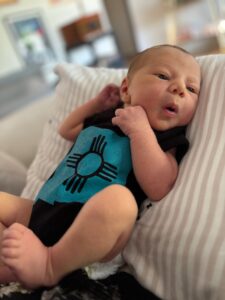 a newborn baby cooing in a brown and teal outfit