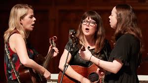 a group of women sing and play instruments together