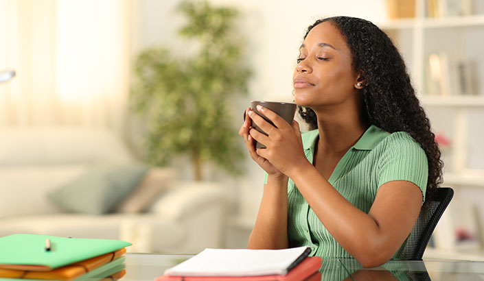 Teacher sitting at desk smelling coffee and reflecting on day.
